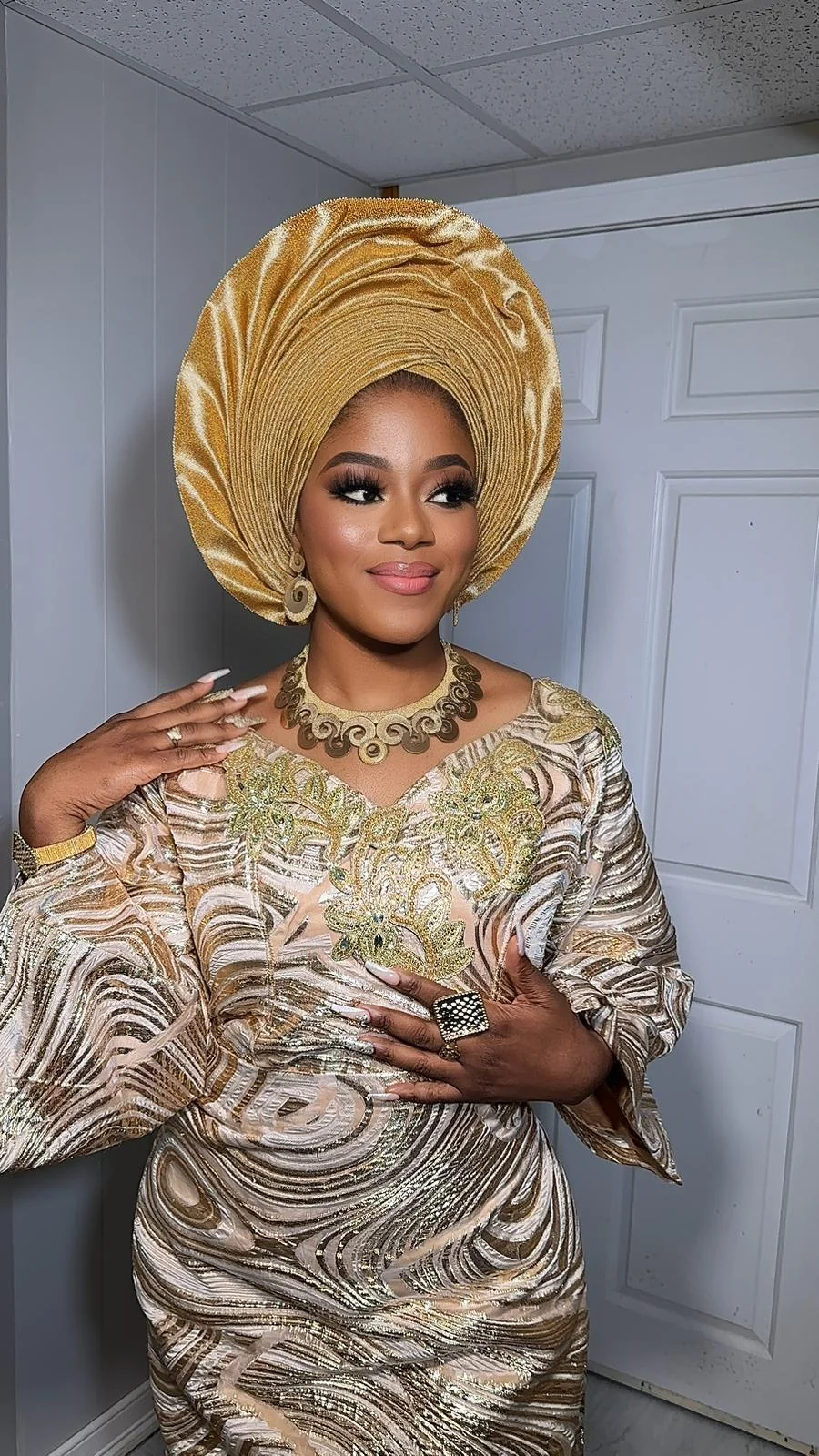 Woman in gold attire wearing a full fan-shaped gold gele